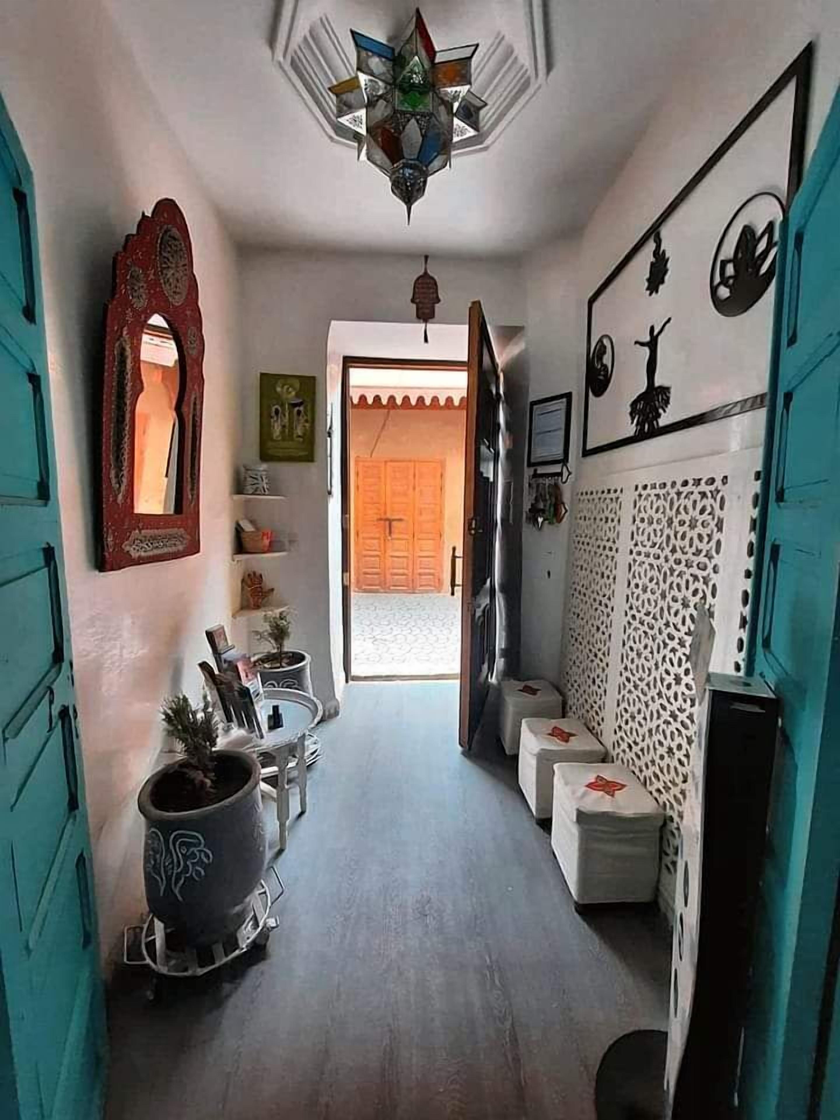A narrow hallway with a ceiling fan, a mirror, and a potted plant.
