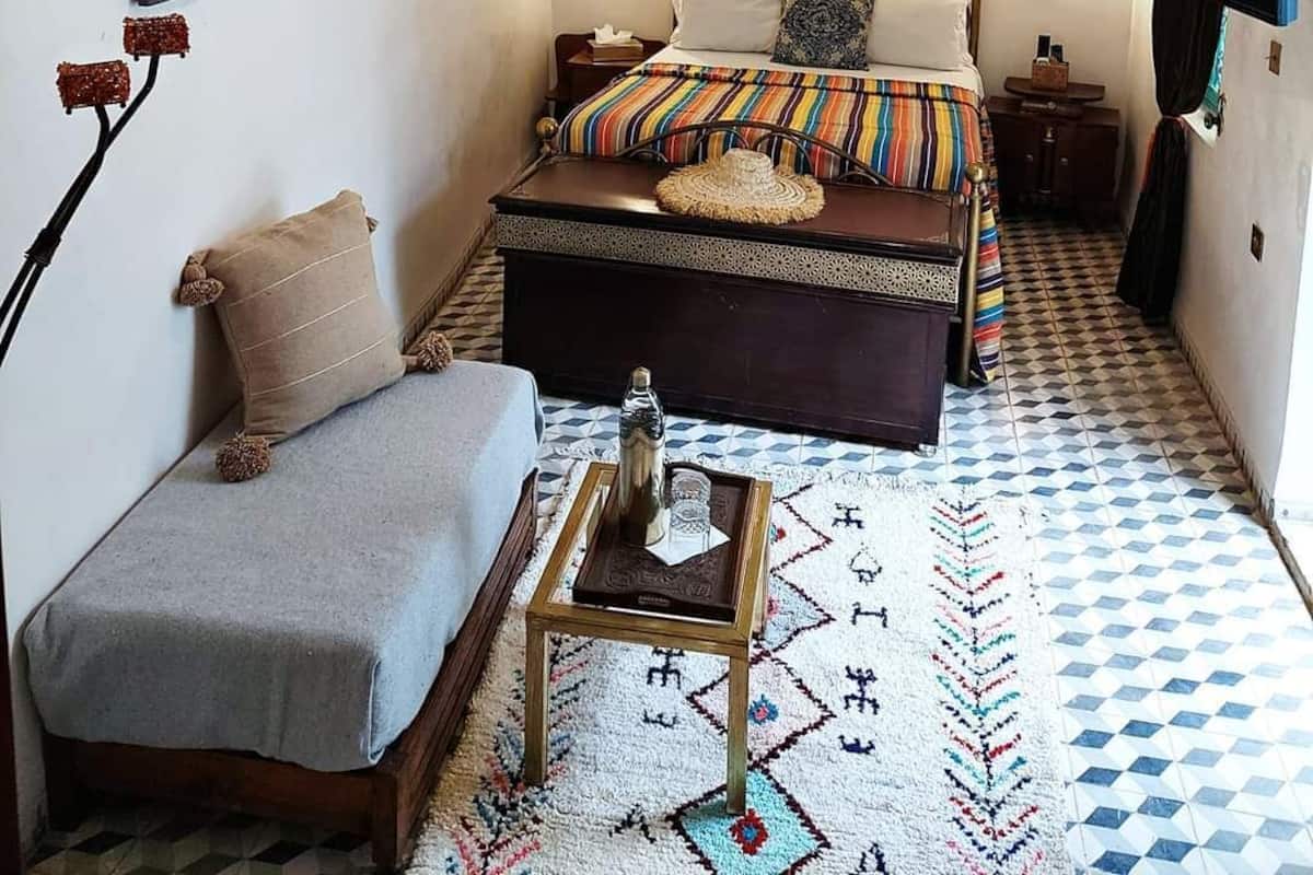 Un dormitorio acogedor con cama, mesitas de noche, lámpara colgante y televisor en la pared.