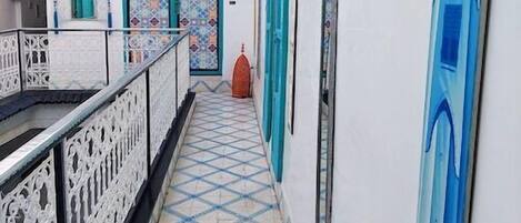 A corridor with a tiled floor, white walls, and blue doors.