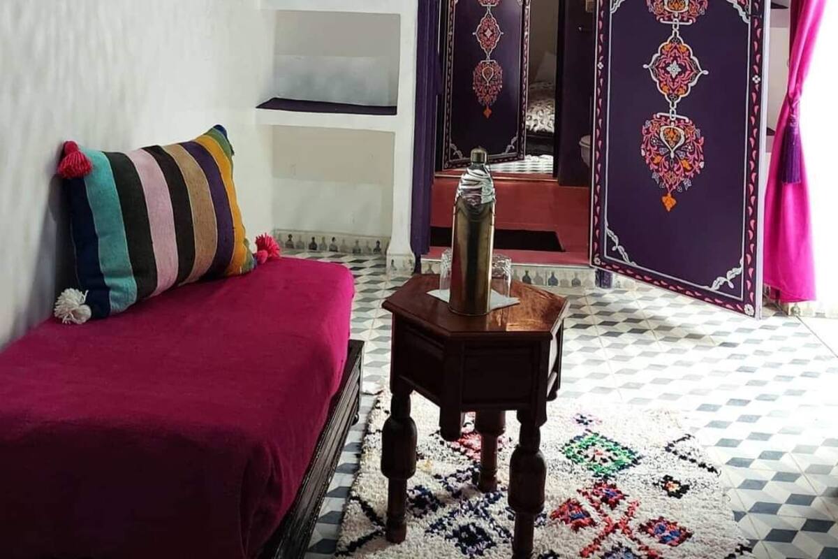 Una habitación con una cama, una mesita pequeña y una puerta de detalles elaborados.