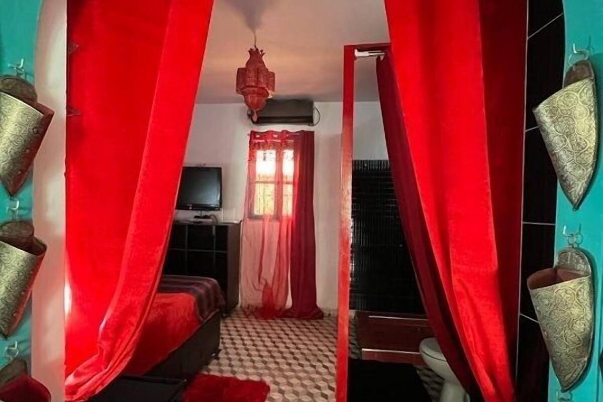 Una habitación con suelo de estampado geométrico, un sofá, un televisor y una cortina roja.