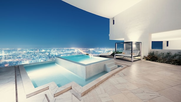 A modern outdoor pool area with a city view, a lounge chair, and a built-in heater.