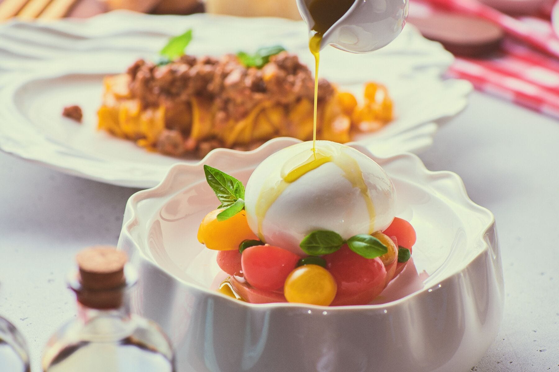 Uma sobremesa com ovo escalfado, frutas frescas e molho sendo servido por cima.