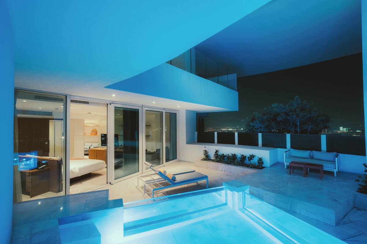 A modern outdoor living area with a pool, a lounge chair, and a sofa.
