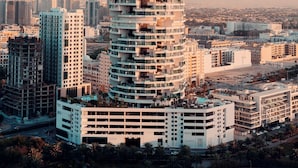 A tall, cylindrical hotel with multiple balconies, surrounded by other buildings in a cityscape.