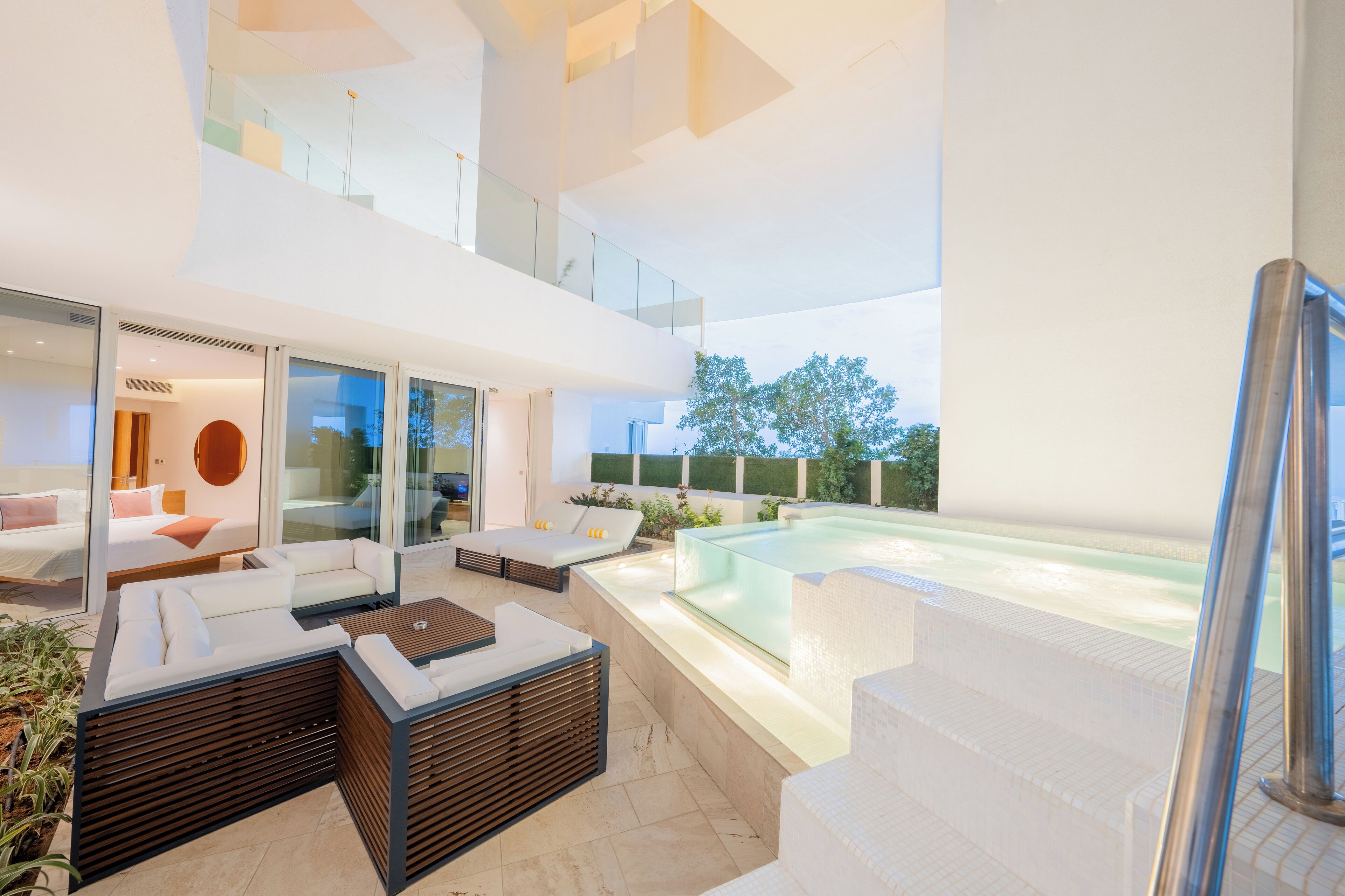 A modern outdoor living area with a pool, seating, and a staircase.