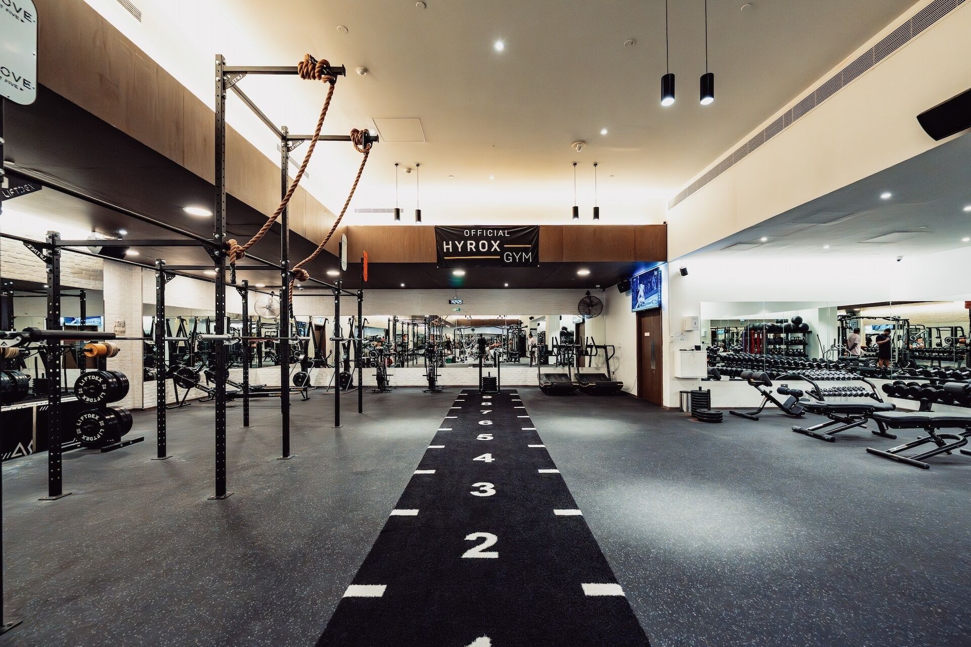 Une salle de sport équipée de matériel de musculation, de tapis de course et dotée d’un mur recouvert de miroirs.
