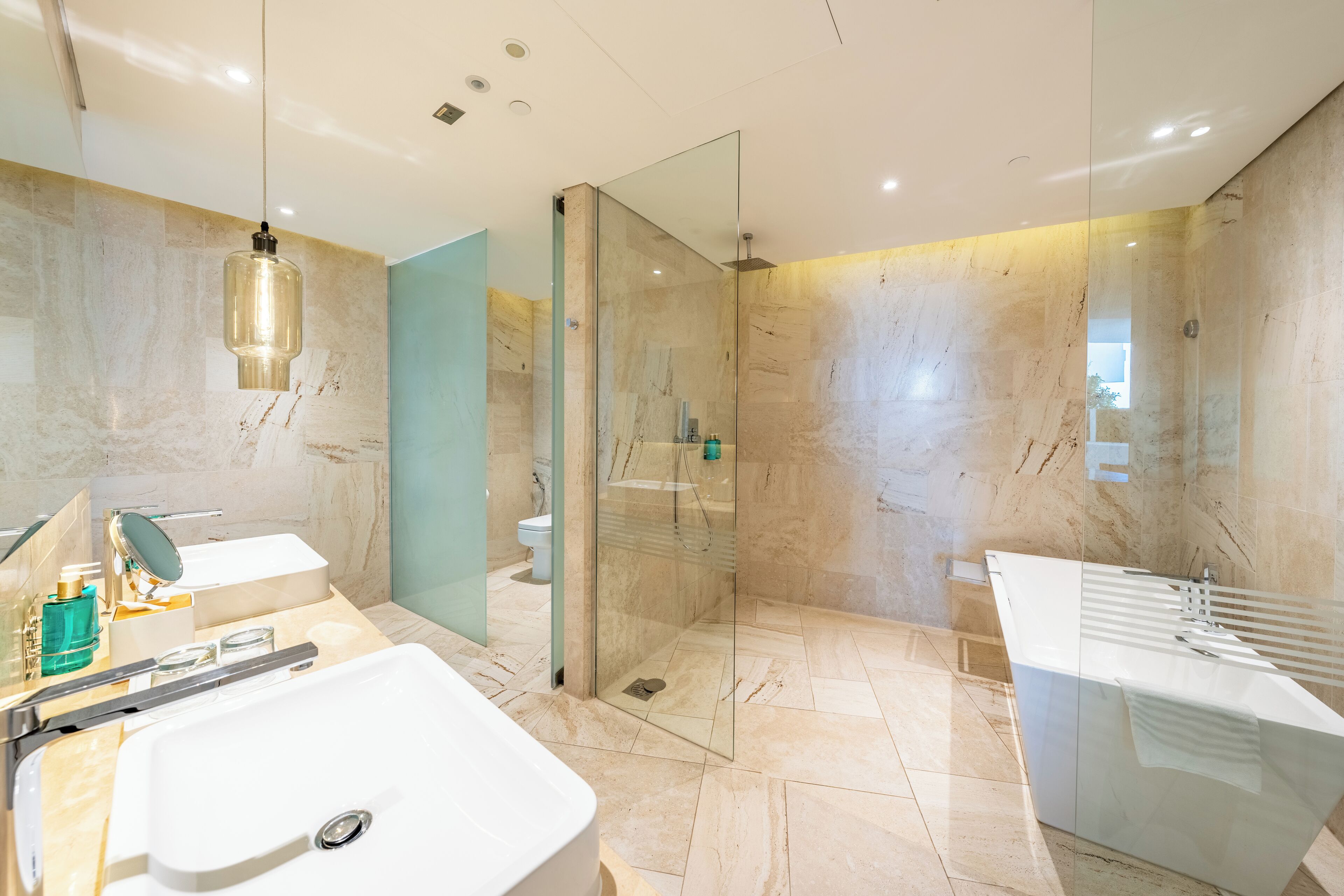 A modern bathroom with a large sink, a glass-enclosed shower, and a separate bathtub.