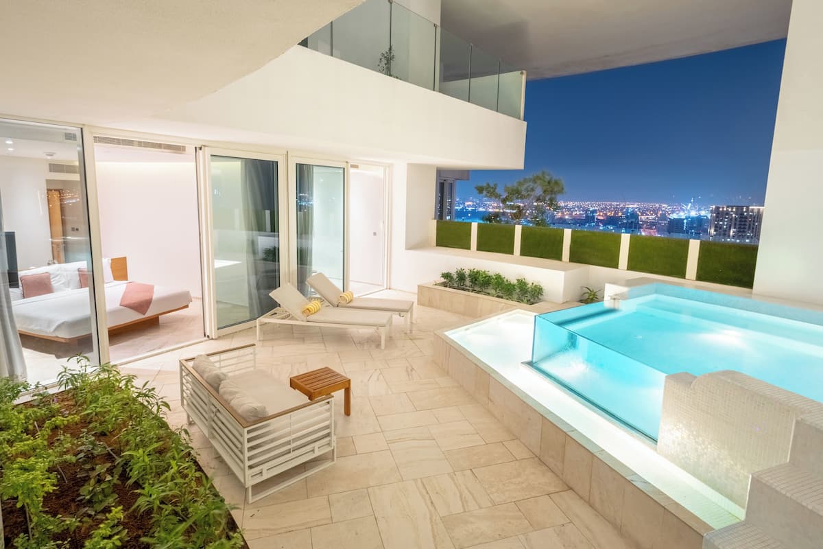 A modern outdoor living area with a pool, lounge chairs, and a city view.