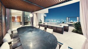 A modern outdoor dining area with a large table and chairs, a wooden ceiling, and a city view.