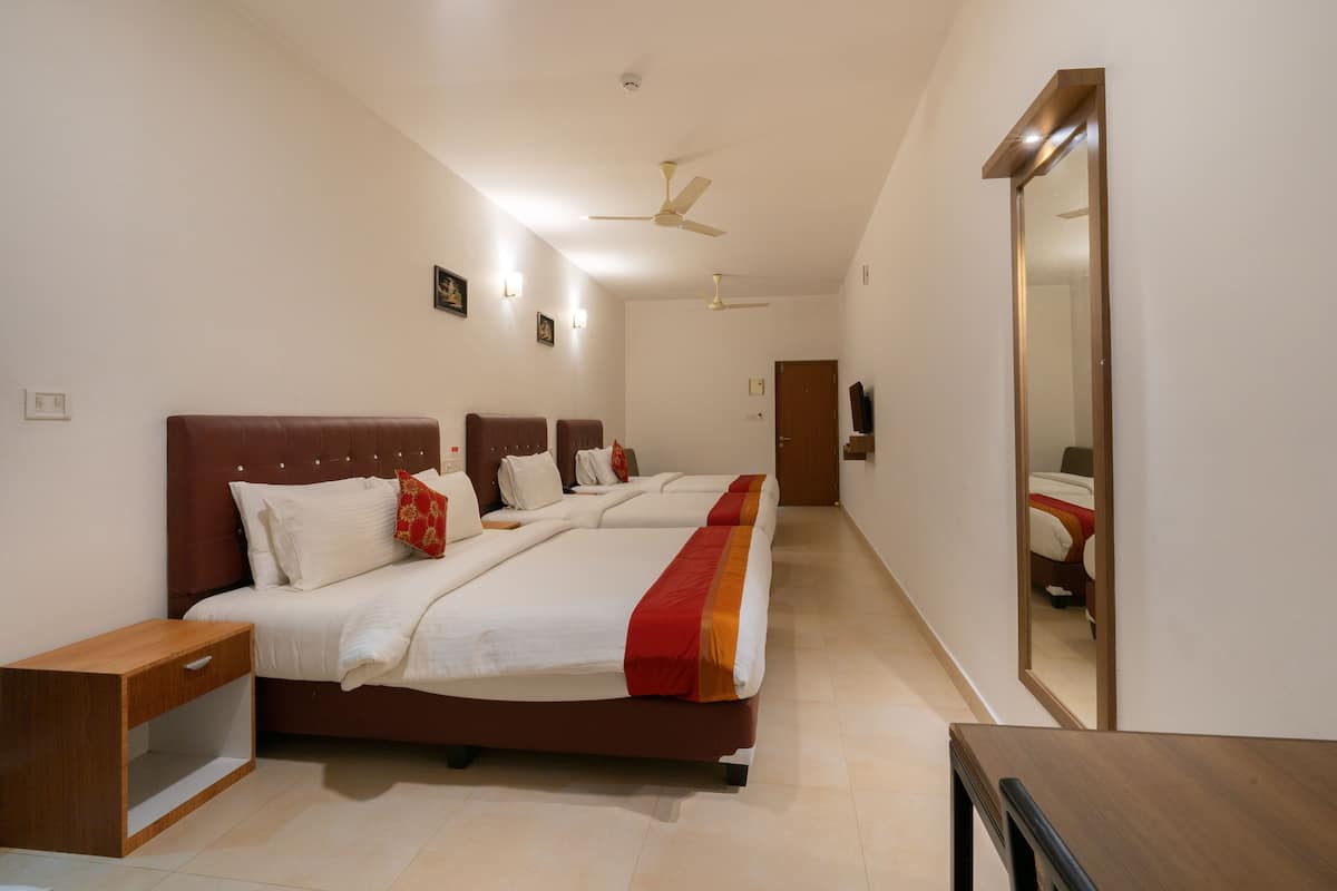 A hotel room with a large bed, bedside tables, a wardrobe, and a ceiling fan.