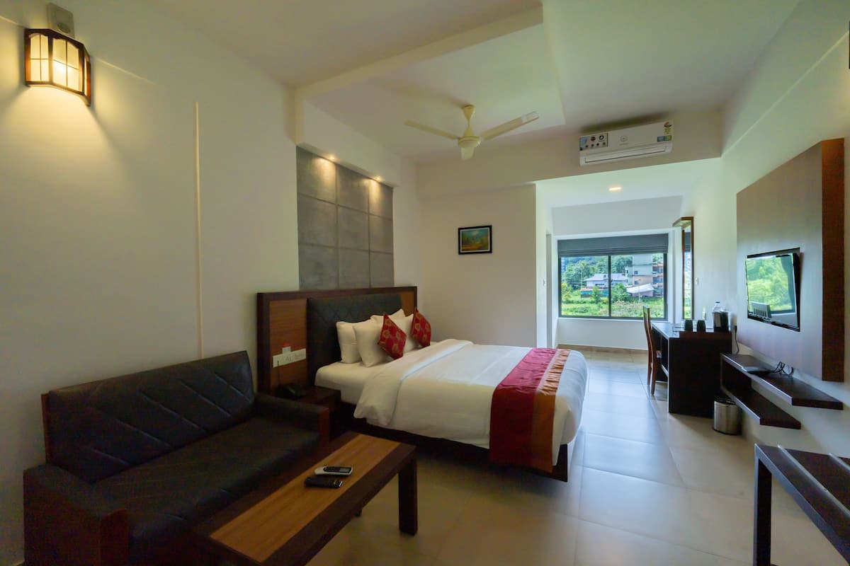 A modern hotel room with a bed, a sofa, a desk, a TV, and a window with a view.