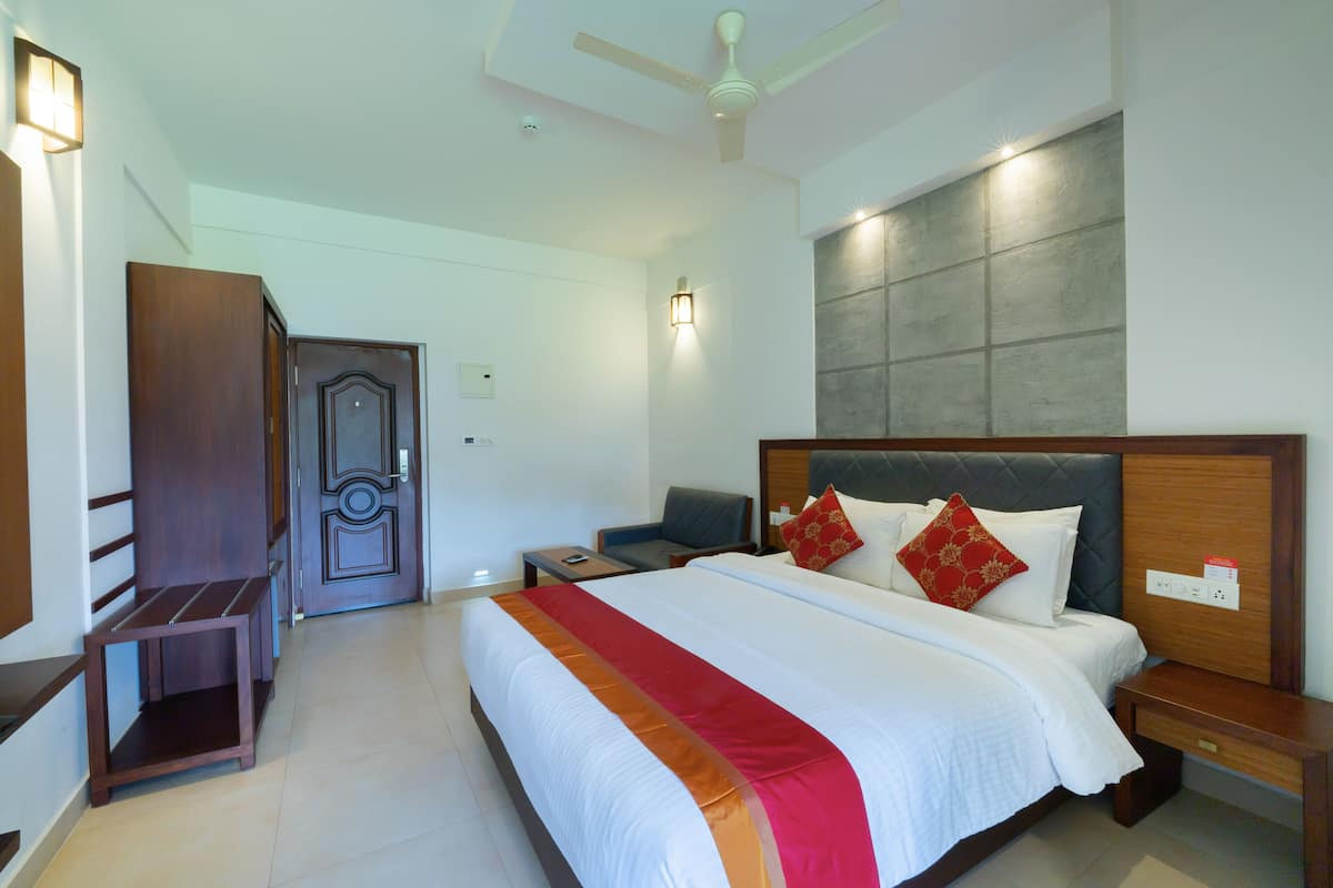 A hotel room with a large bed, bedside tables, a desk, and a wardrobe.