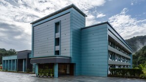 A modern building with a flat roof and a corner entrance. - The Sanihara Hotel & Resort (Vythiri)