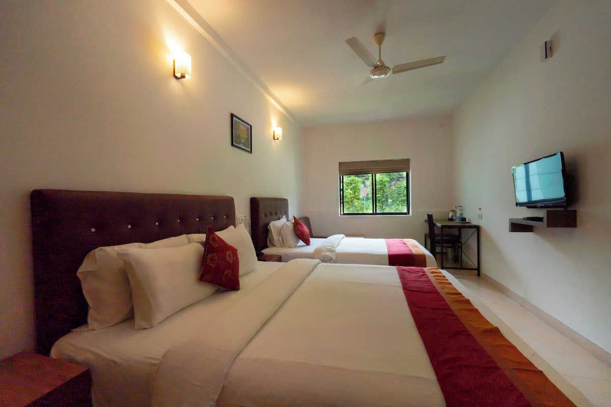 A hotel room with two beds, a ceiling fan, a TV, and a window.