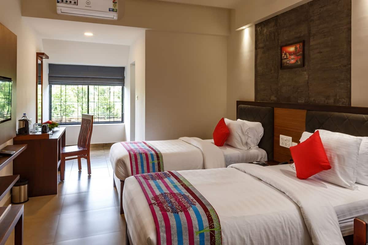 A hotel room with two beds, a desk, a chair, and a large window.