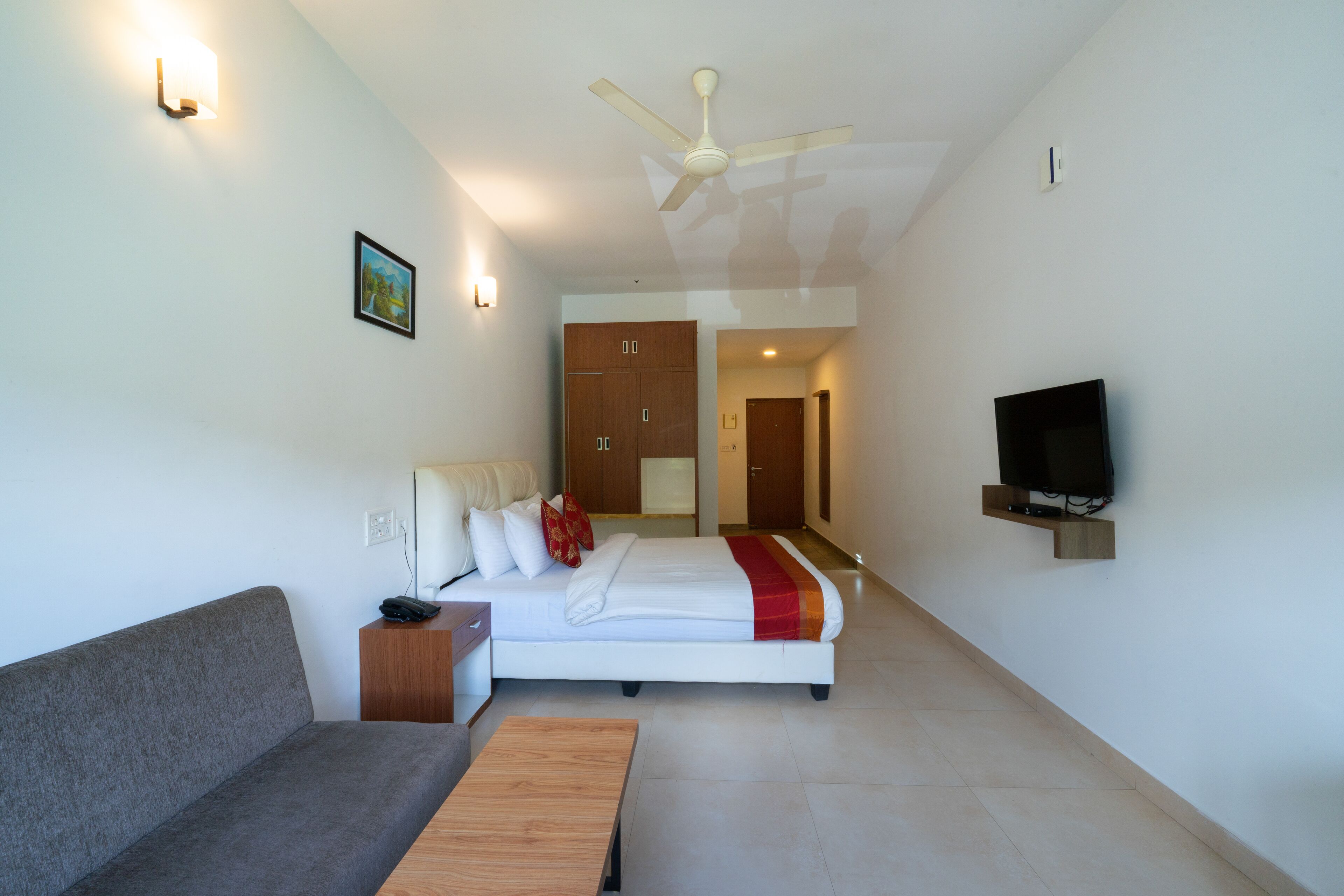 Una habitación de hotel moderna con una cama, un sofá, un televisor y un ventilador de techo.