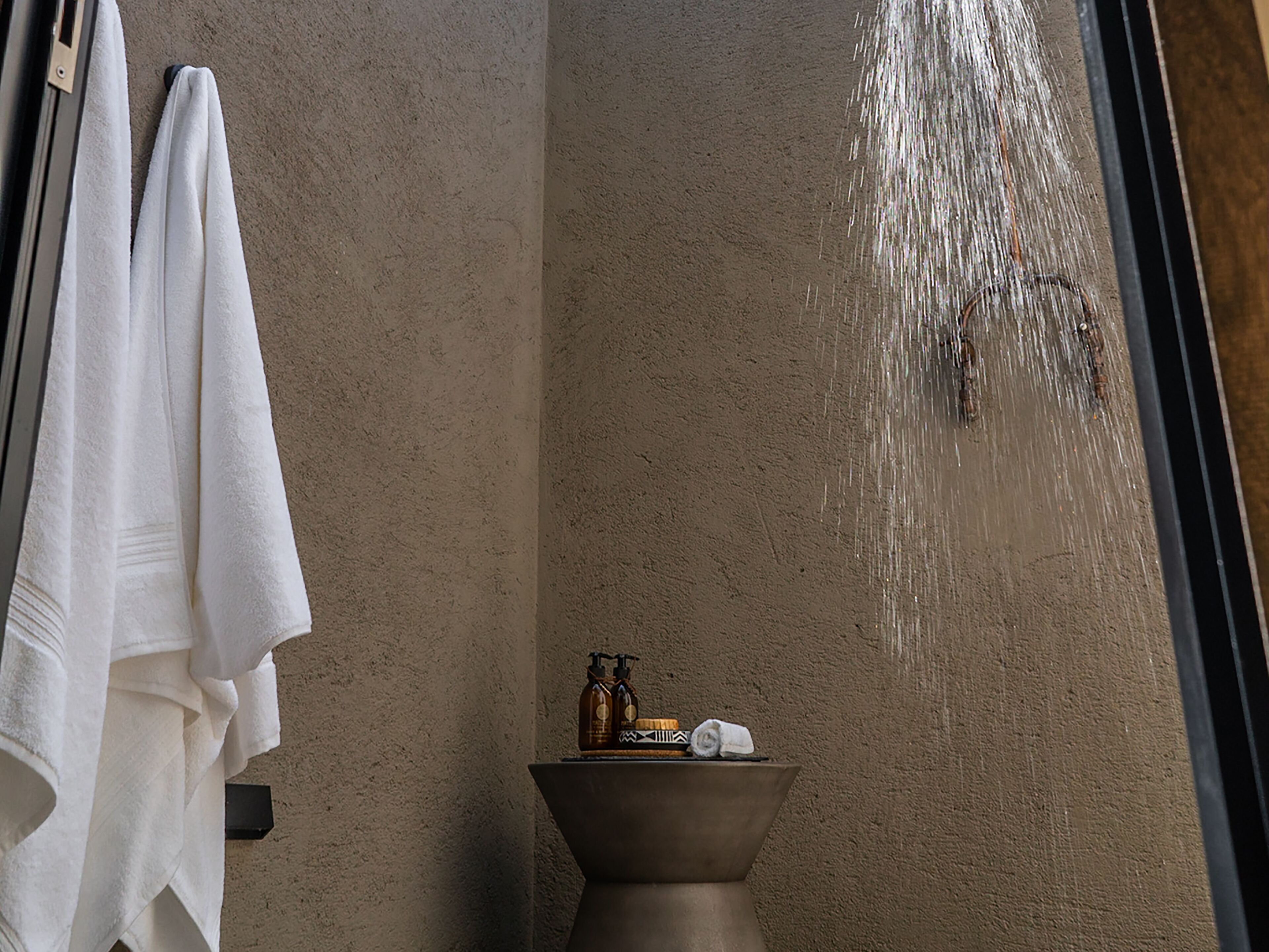 A bathroom with a beige textured wall, a white towel hanging on a rack, and a small sink with toiletries.