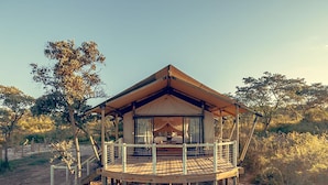 A wooden, elevated structure with a balcony, surrounded by natural vegetation.