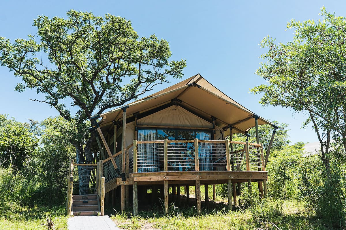 Een houten chalet met een balkon, omringd door bomen en een heldere lucht.