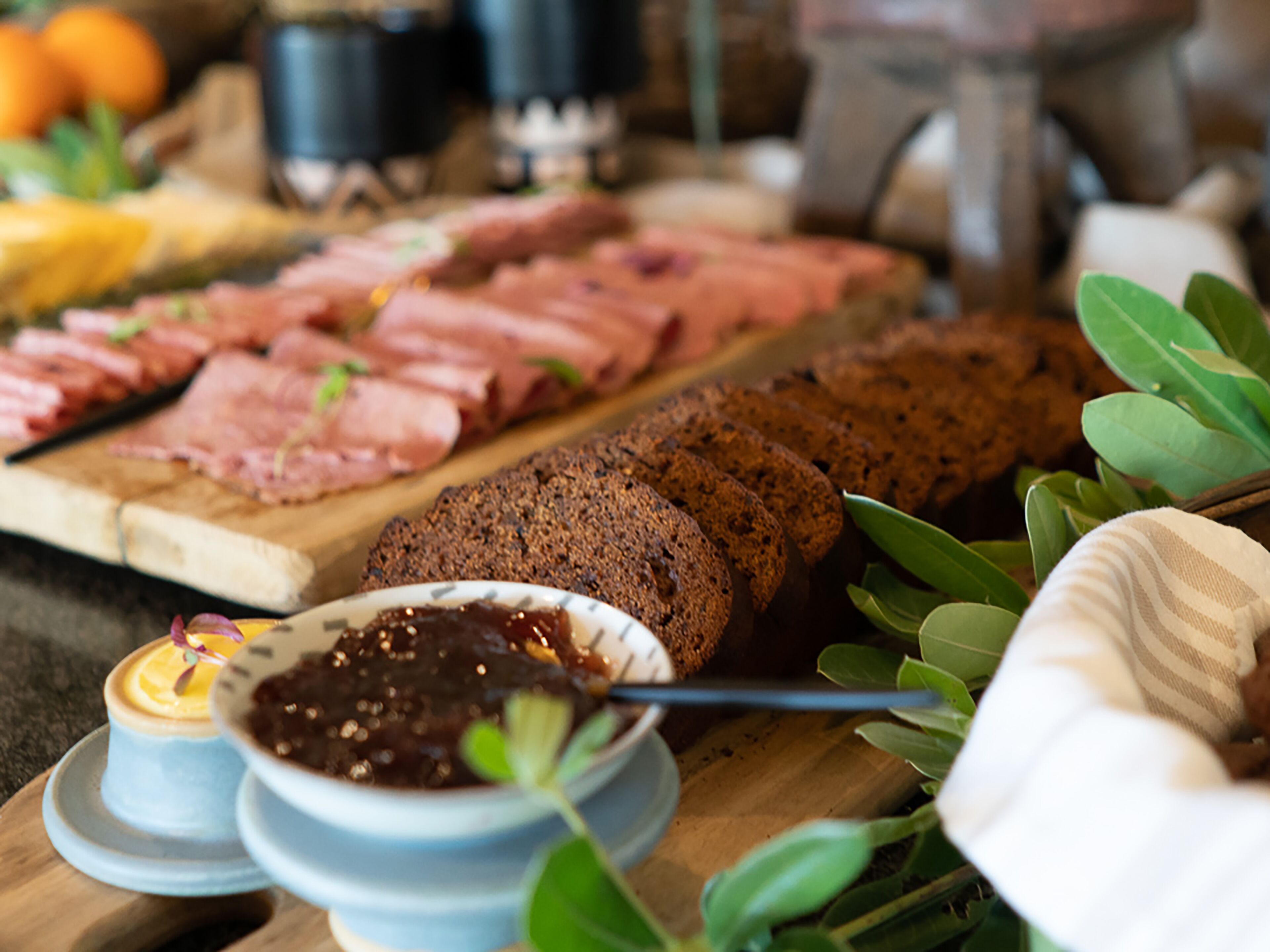 A charcuterie board with various meats and breads, accompanied by small bowls of condiments.