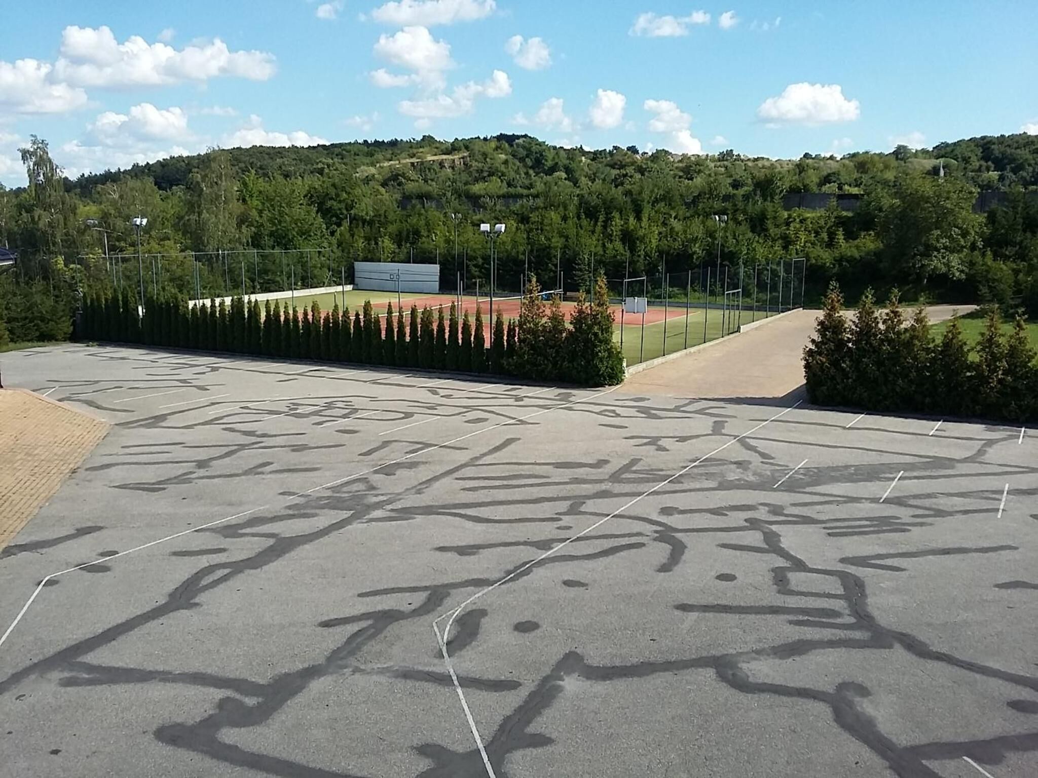 Un estacionamiento con espacios delimitados y un campo deportivo al fondo.