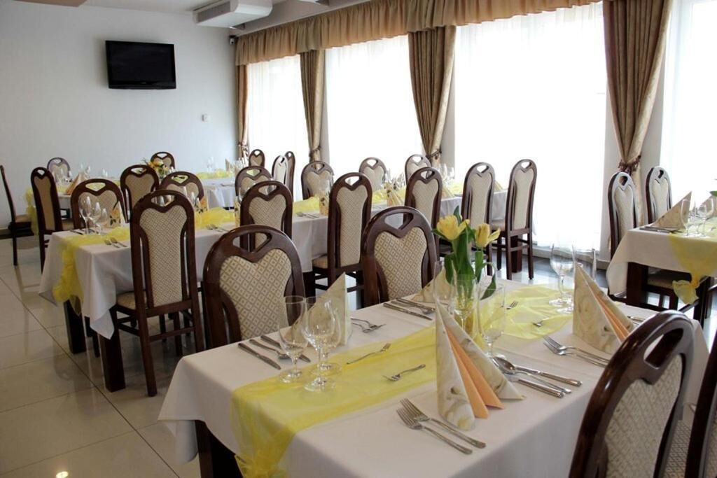 Un comedor con varias mesas dispuestas para una comida, cada una con sillas y cubertería y cristalería.