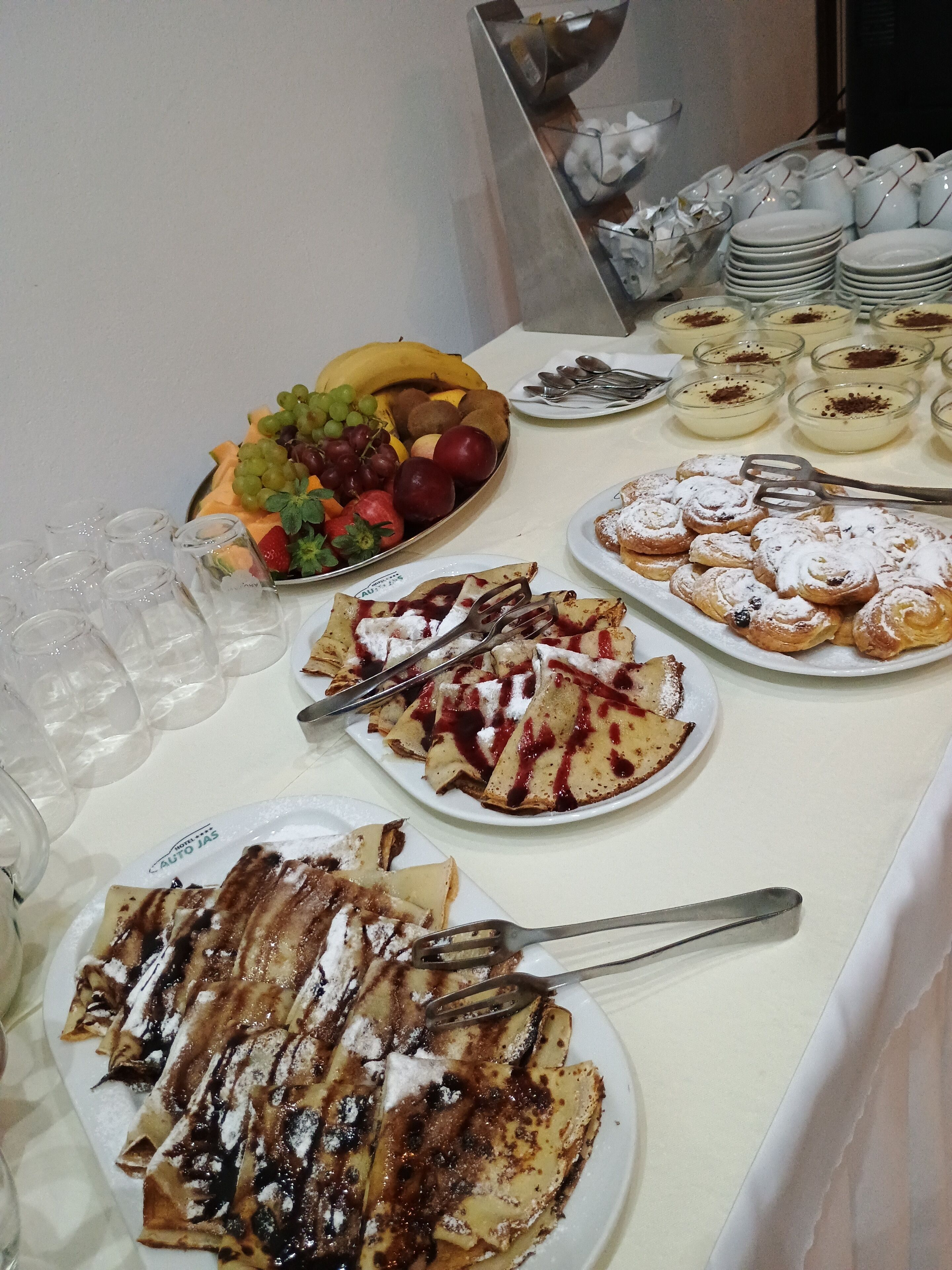 Ett buffébord med olika rätter, inklusive frukt, crêpes och desserter.
