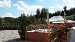 An outdoor seating area with tables and chairs, surrounded by potted plants and flowers. - Hotel Auto Jas (Nitra)