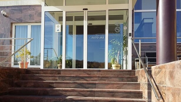 A hotel entrance with a staircase leading up to a glass door. - Hotel Auto Jas (Nitra)