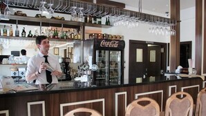A bar area with a bartender, a Coca-Cola refrigerator, and heart-shaped chairs. - Hotel Auto Jas (Nitra)