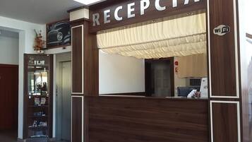 A reception area with a sign reading "RECEPCIA" and a Wi-Fi symbol.