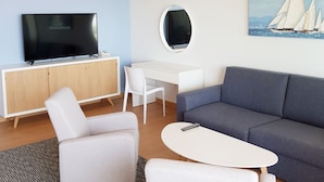 A modern living room with a flat-screen TV, a desk, a sofa, and a painting of sailboats. - Abalone Apartments (Crikvenica)
