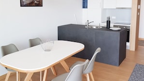 A modern kitchen with white cabinets, a central island, and pendant lighting. - Abalone Apartments (Crikvenica)