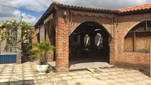 A brick building with a tiled patio, arched doorways, and a potted plant. - Hotel Sun Valley (Senhor Do Bonfim)