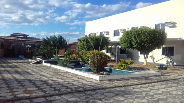 A courtyard with a swimming pool, potted plants, and a building with multiple air conditioning units. - Hotel Sun Valley (Senhor Do Bonfim)