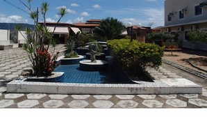 A courtyard with a fountain, potted plants, and a tiled floor. - Hotel Sun Valley (Senhor Do Bonfim)