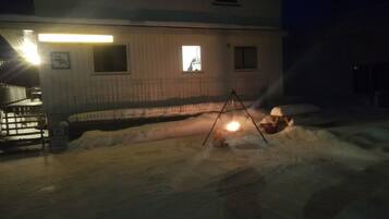 A building with a snow-covered ground, a swing set, and a bright light source.