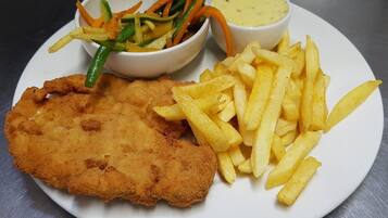 Ein Teller mit einem panierten Fischstäbchen, Pommes Frites und zwei Beilagen.