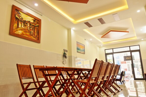 A conference room with wooden chairs, a painting on the wall, and a ceiling with recessed lighting. - Gold Stone Homestay Hoi An (Da Nang)