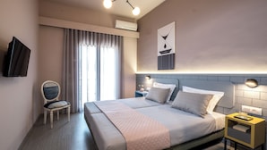 A modern hotel room with a large bed, a bedside table, a chair, a TV, and a window with curtains. - apt27 (Nafplio)