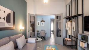 A modern living room with a sofa, coffee table, and a dining area in the background. - apt27 (Nafplio)