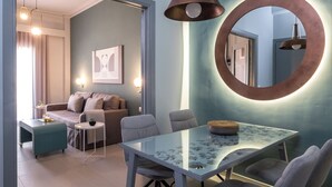 A modern dining area with a glass table, chairs, and a unique circular mirror on the wall. - apt27 (Nafplio)
