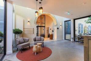 A modern lobby with a round red rug, two sofas, a wooden coffee table, and a large arched doorway. - Hotel Indigo Larnaca by IHG (Larnaca)