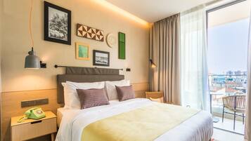 Habitación de hotel con una cama grande, una mesita de noche con teléfono y vistas a la ciudad por la ventana.