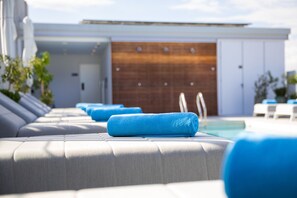A modern poolside area with lounge chairs and a wooden door in the background.