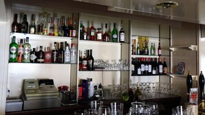A bar area with shelves stocked with various liquor bottles and glasses. - The Nags Head (Thirsk)