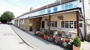 A two-story building with a cafe on the ground floor, outdoor seating, and flower boxes. - The Nags Head (Thirsk)