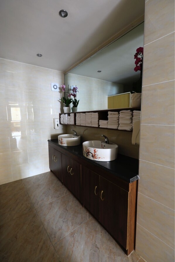 Un baño moderno con dos lavabos, un mueble de tocador de madera oscura y un espejo grande.