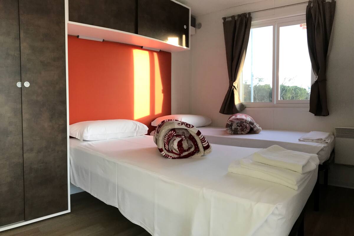 Une chambre d’hôtel avec un lit, une fenêtre avec des rideaux, un radiateur et une armoire.